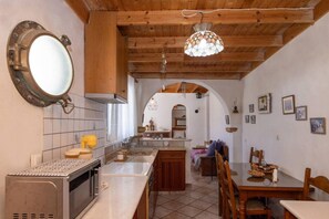 Una cocina con vigas de madera, un ventanal grande y un comedor con mesa y sillas.