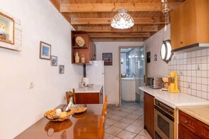 Una cocina con armarios de madera, salpicadero de azulejos y un comedor con mesa y sillas de madera.