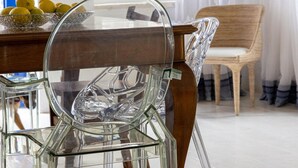 En matplats med ett träbord, genomskinliga stolar i glas och en stol i rotting.