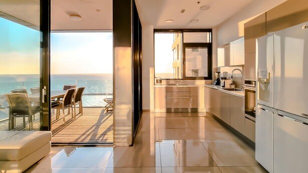 A modern kitchen with a view of the ocean, a balcony with seating, and a large refrigerator. - Hayarkon Blue Sea I in Tel Aviv-Yafo (Tel Aviv-Yafo)