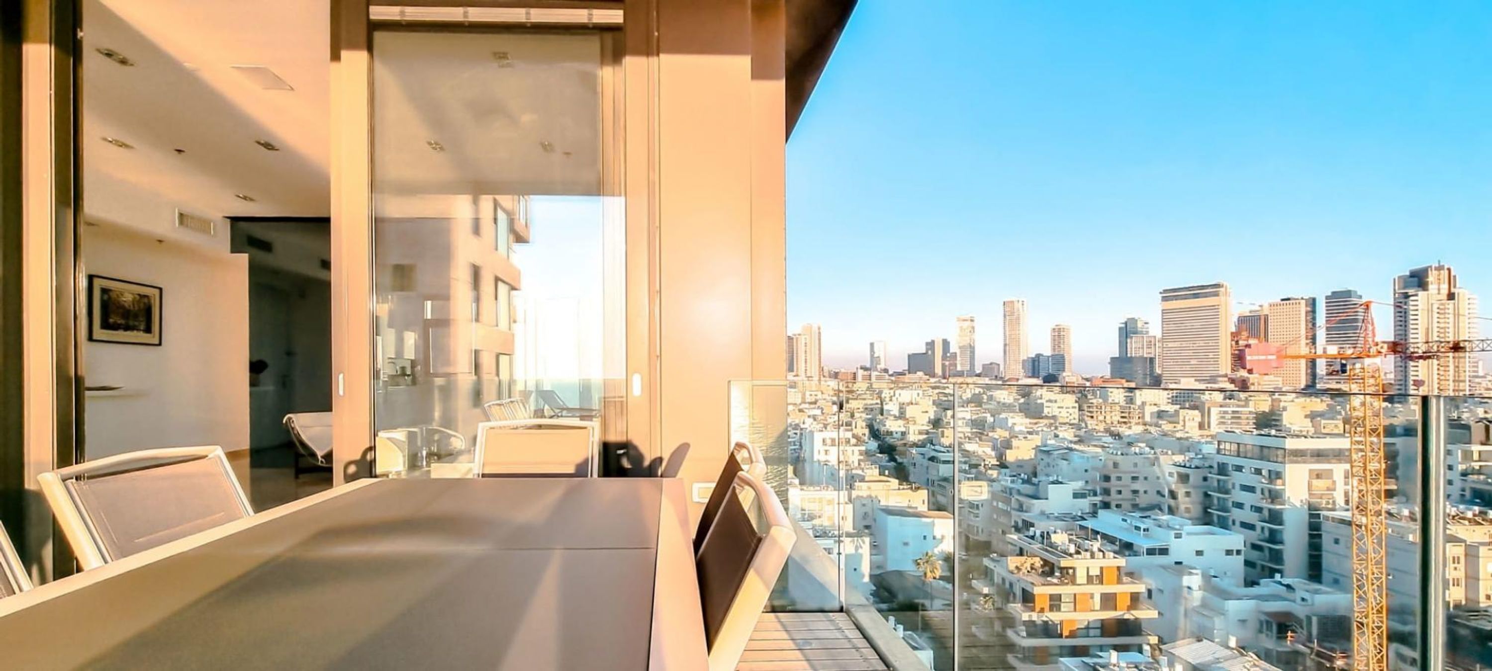 Un balcon moderne offrant une vue sur la ville, un coin repas avec une table et des chaises, et une cloison en verre.