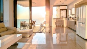 A modern living room with a sofa and a dining area with chairs, leading to a balcony with a view of the sea. - Hayarkon Blue Sea I in Tel Aviv-Yafo (Tel Aviv-Yafo)