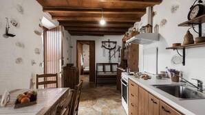 Eine rustikale Küche mit Steinböden, Holzschränken und einer Essecke mit Tisch für zwei Personen.