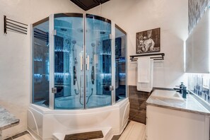 A modern bathroom with a glass-enclosed shower, a marble sink, and a towel rack. - Loft N' Loaded: Downtown Wichita Luxury Loft (Wichita)