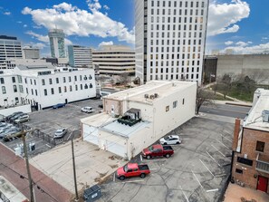 A parking lot with several vehicles, including a red pickup truck and a white car. - Loft N' Loaded: Downtown Wichita Luxury Loft (Wichita)