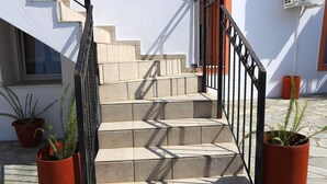 A staircase with beige steps and black railings, flanked by potted plants. - Nikolaou Apartments Upper Floor (Keramidi)