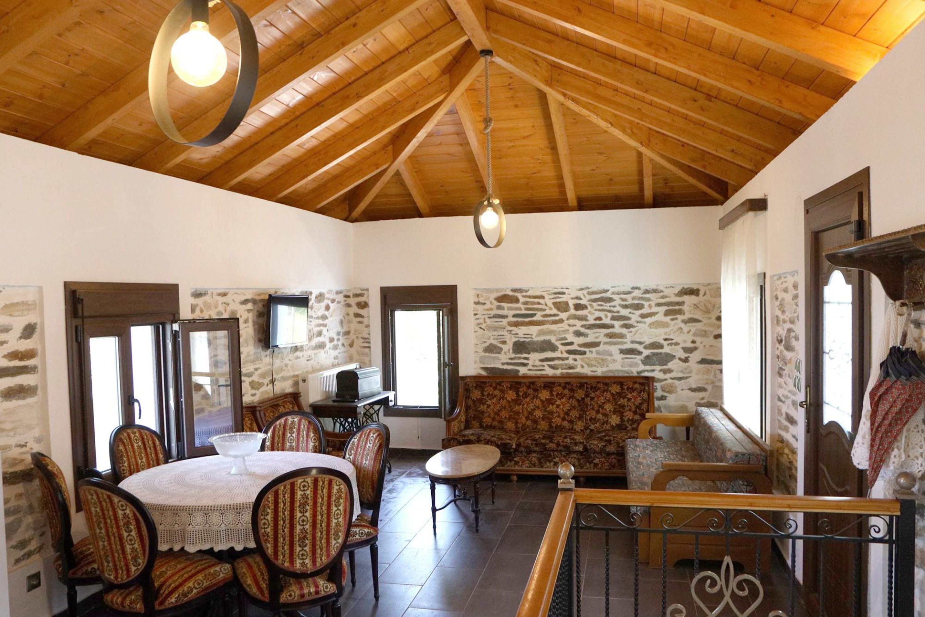 Un'area pranzo con un tavolo rotondo e sedie, un divano e una scala con ringhiera.