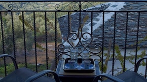 A balcony with a table and chairs, overlooking a coastal landscape with hills and the sea. - Archontiko Nikolaou Keramidi (Keramidi)