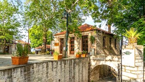 A stone building with a tiled roof, surrounded by trees and potted plants. - Archontiko Nikolaou Keramidi (Keramidi)