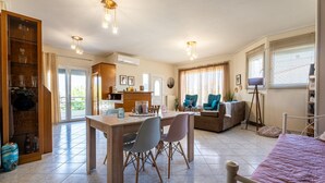 Un grand espace de vie comprenant une table à manger en bois, des chaises, un canapé et un lit. Il y a également un coin cuisine avec un réfrigérateur et une fenêtre.