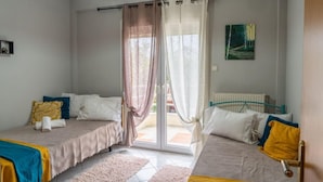 Une chambre avec deux lits, une grande fenêtre avec des rideaux, un radiateur et un tableau au mur.