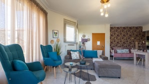 Un salon moderne avec des fauteuils turquoise, un canapé gris et une table basse en bois.