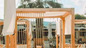 Un espace extérieur aménagé avec des meubles en bois, comprenant un hamac et un banc rembourré.