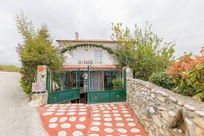 A rustic house with a stone wall and a red and white patterned entrance.
