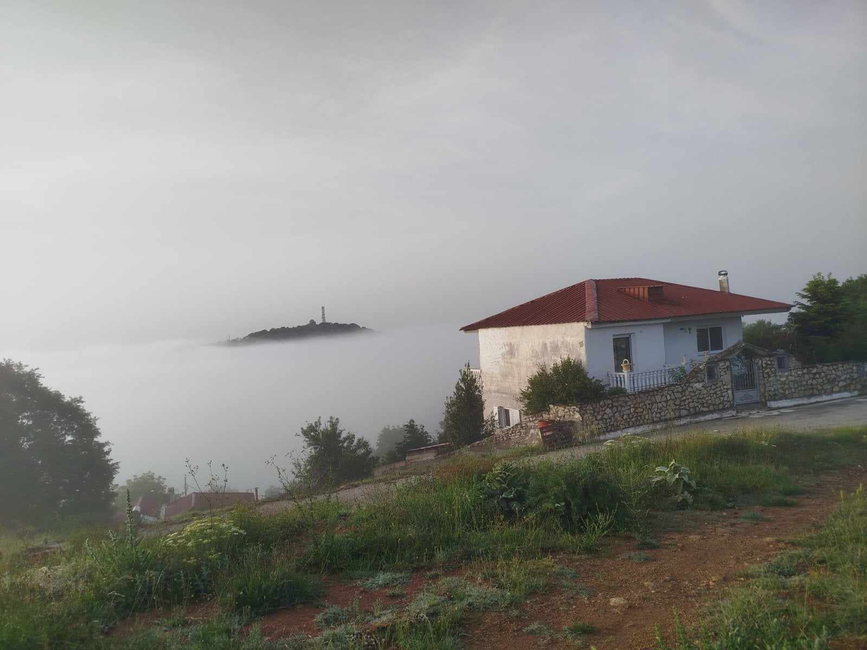 A house with a red roof, white walls, and a stone foundation.
