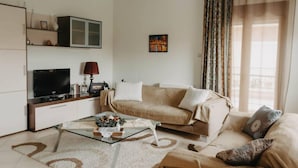 Una sala de estar con un sofá, una mesa de centro, un televisor y un mueble aparador.