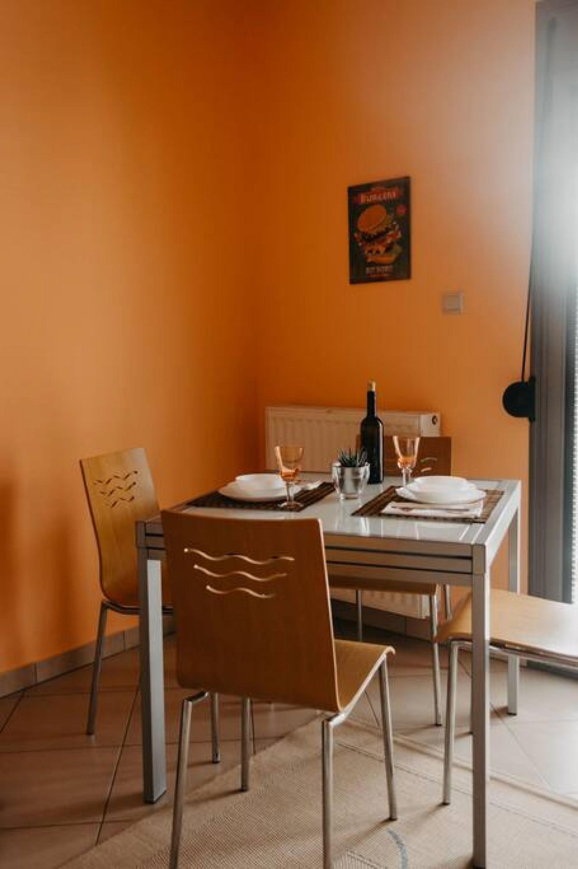 Ein Essbereich mit Tisch für zwei Personen, Stühlen, einem Heizkörper und einem Bild an der Wand.