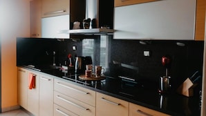 Una cocina moderna con encimeras negras, armarios color beige y una campana extractora de acero inoxidable.