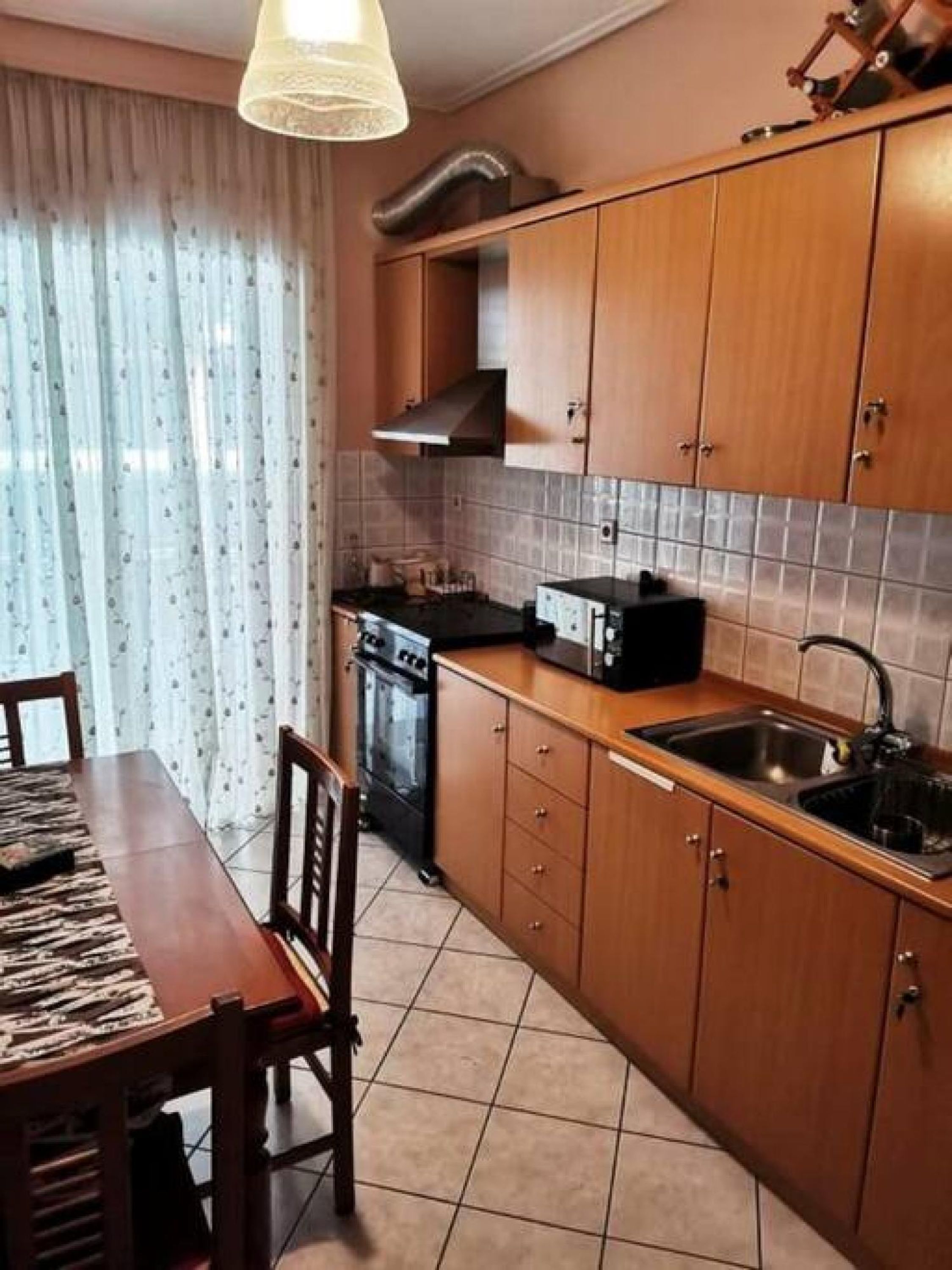Una cocina compacta con armarios de madera, horno empotrado, microondas y pileta.