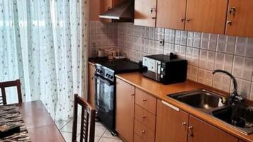 Una cocina compacta con armarios de madera, horno empotrado, microondas y pileta.