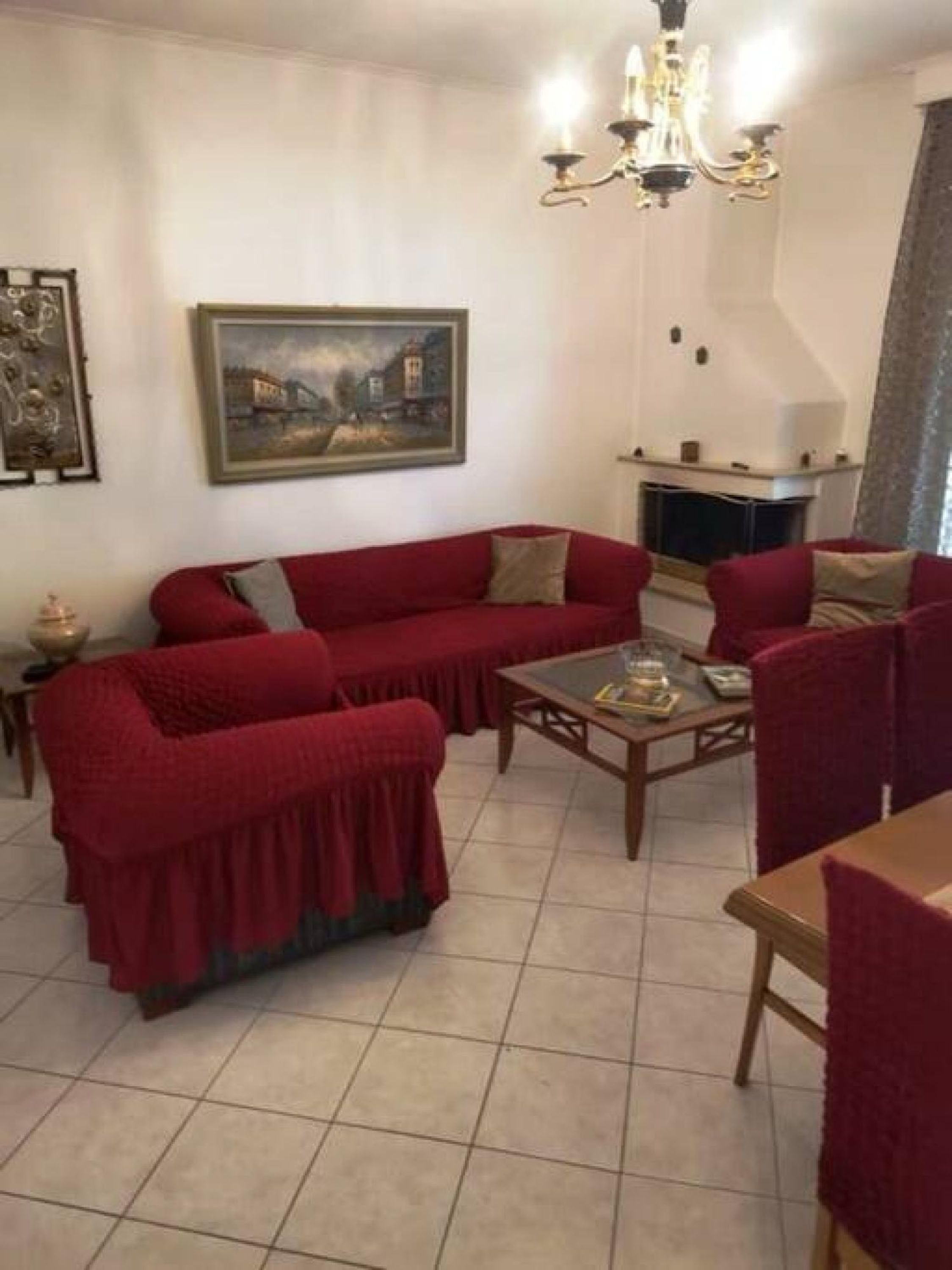 Una sala de estar con un sofá rojo, una mesa de centro de madera, una chimenea y un candelabro.