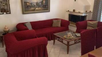 Una sala de estar con un sofá rojo, una mesa de centro de madera, una chimenea y un candelabro.