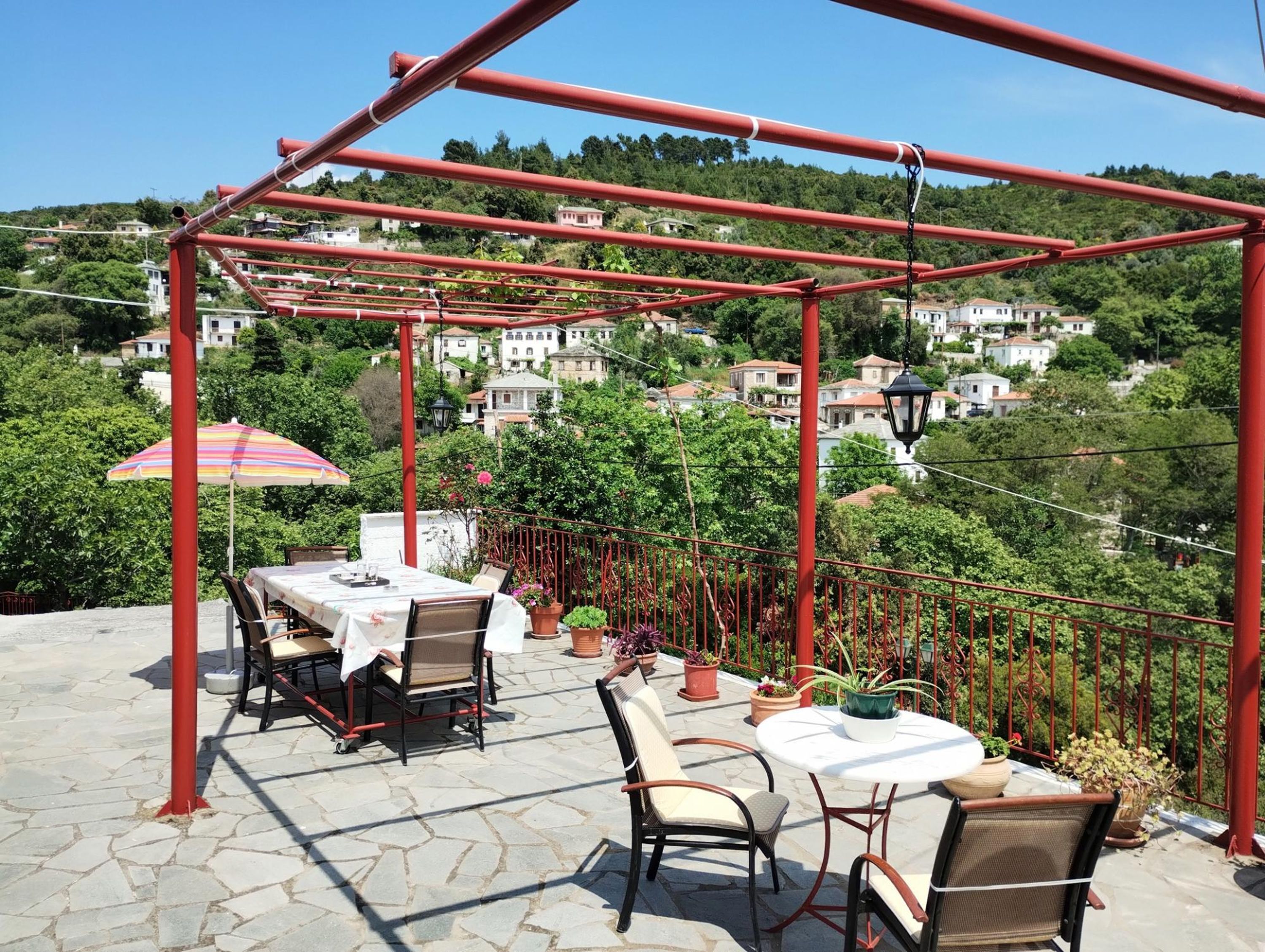 A terrace with a pergola, outdoor seating, and potted plants.