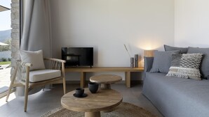 A modern living room with a sofa, a wooden coffee table, a TV, and a wicker chair.