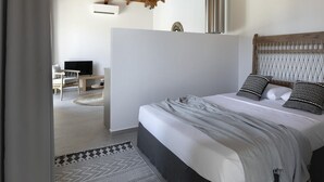 A bedroom with a wooden ceiling, a bed with patterned pillows, a desk with a chair, and a TV.