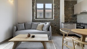 Uma sala de estar moderna com um sofá cinza, uma mesa de centro de madeira e uma parede de pedra.