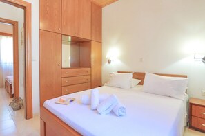 Une chambre d’hôtel avec une armoire en bois, un lit avec du linge de lit blanc et une table de chevet.