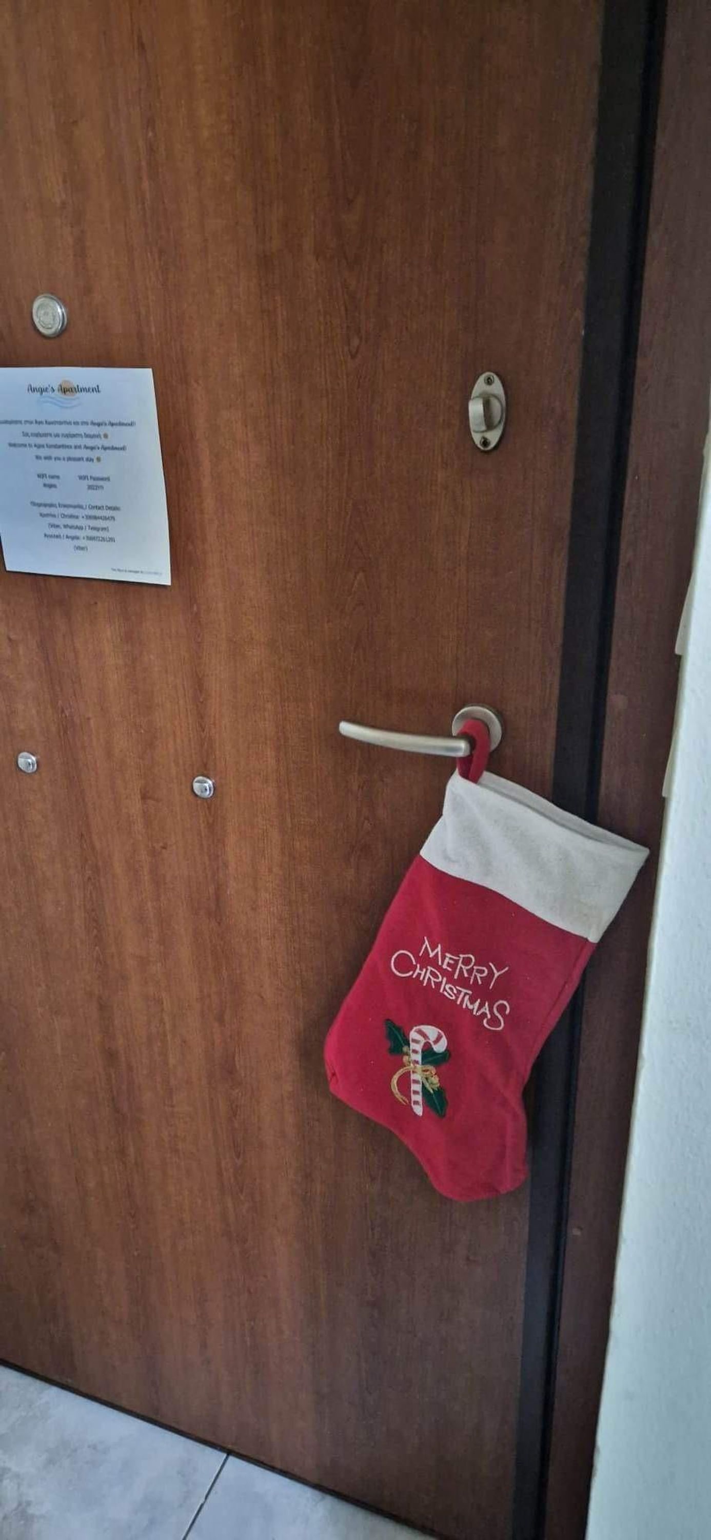 A wooden door with a metal handle and a red Christmas stocking hanging on the door.