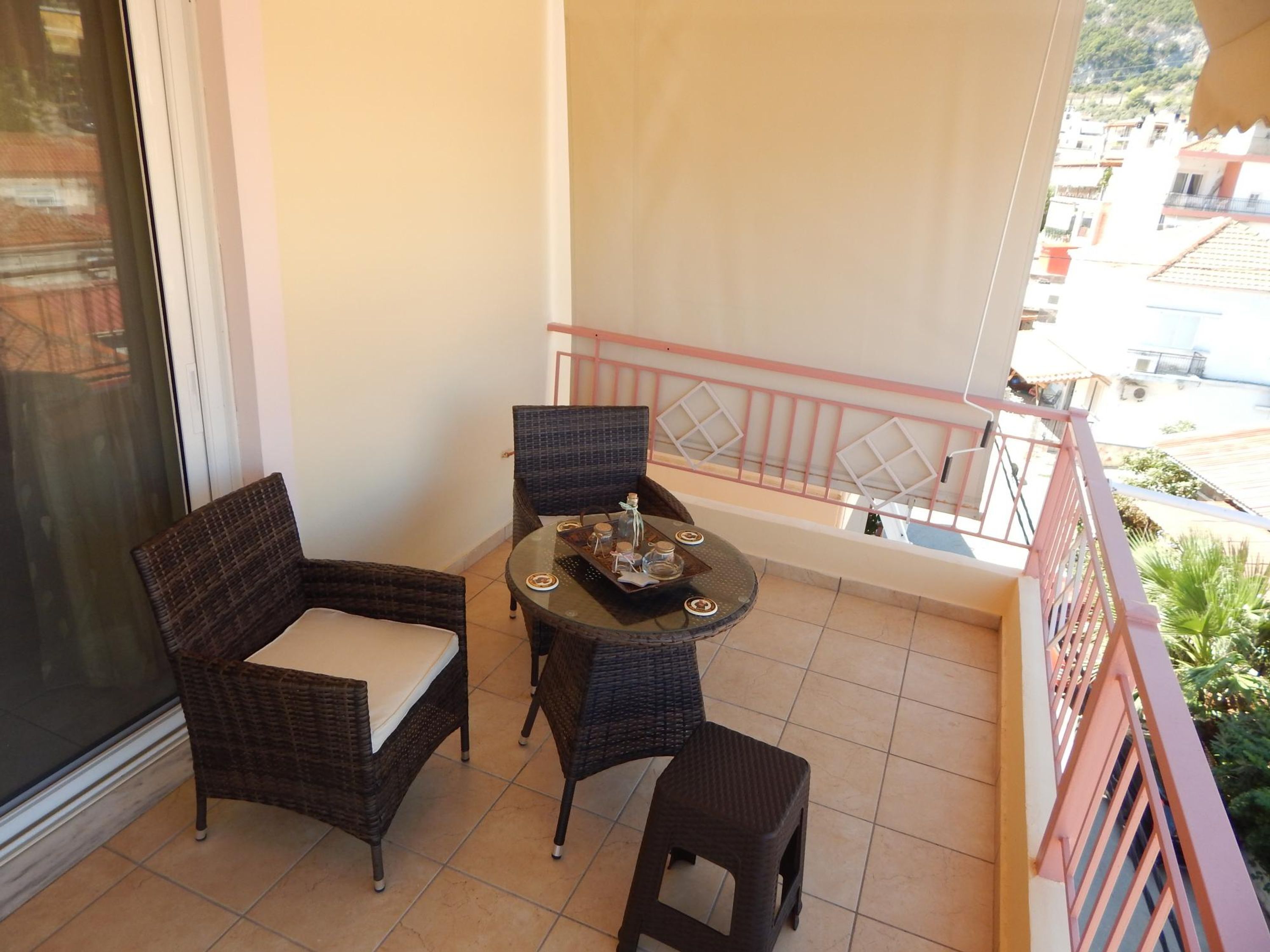 Un balcone con mobili in vimini, un tavolino e vista sulla città.