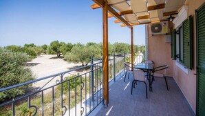 Ein Balkon mit Tisch und Stühlen, einer Pergola und Blick auf Olivenbäume.