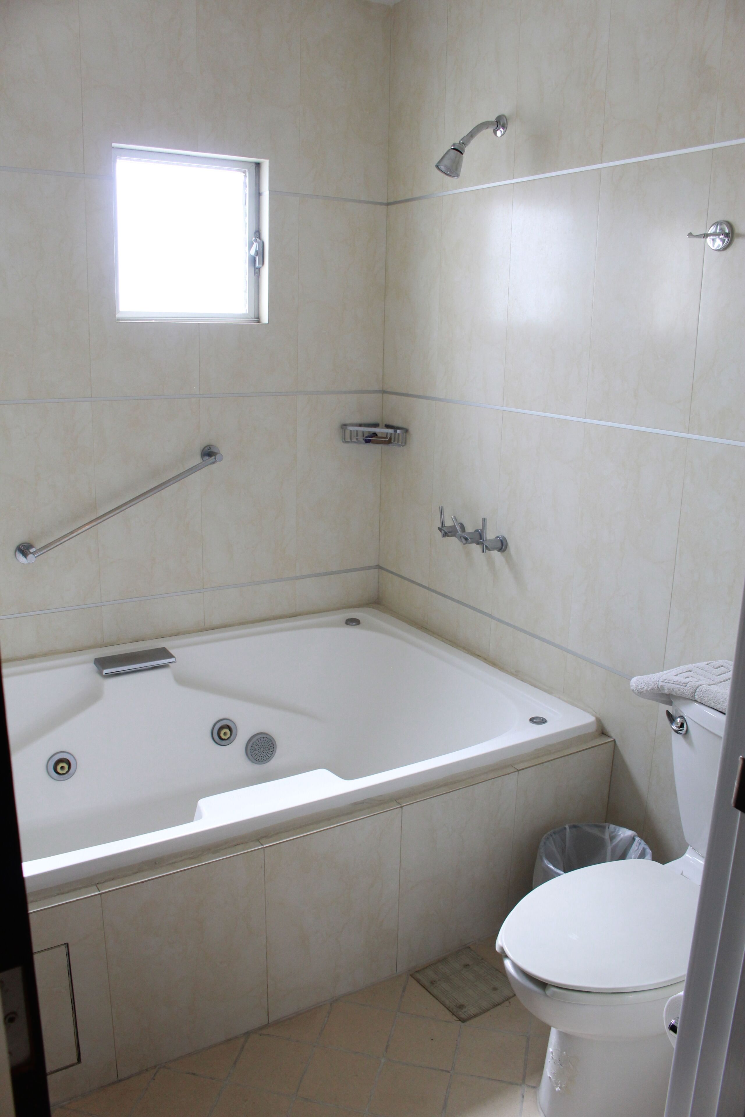 A bathroom with a bathtub, toilet, and a window.