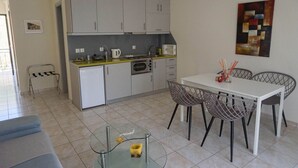 A modern kitchen with grey cabinets, a dining table with metal chairs, and a small glass table with a candle.