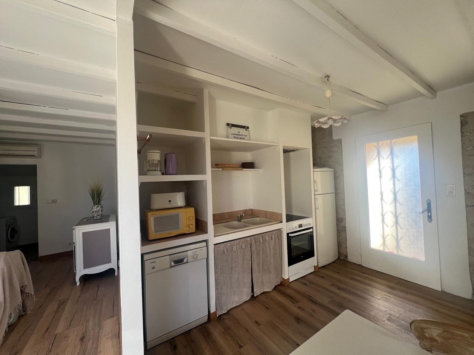Una cocina compacta equipada con lavavajillas, microondas, horno y un refrigerador pequeño.