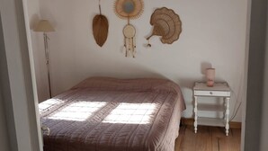 Quarto com cama, mesa de cabeceira e luminária, além de detalhes decorativos nas paredes.