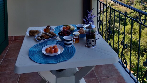 Ein Balkon mit Frühstückstisch, mit Blick auf eine schöne Hügellandschaft.