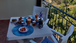 Ein Balkon mit Frühstückstisch, mit Blick auf eine gebirgige Landschaft.