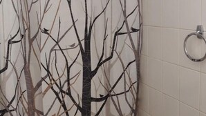 Ein Badezimmer mit Toilette, Waschbecken und einer Duschvorhang mit Abbildung von kahlen Bäumen.