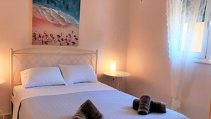 Ein ordentlich bezogenes Bett mit weißen Leinen und zwei Kissen, an beiden Seiten mit Nachttischen mit Lampen, in einem Zimmer mit einem großen Gemälde über dem Bett.