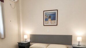Een hotelkamer met een bed, twee nachtkastjes met lampen, een schilderij aan de muur en een airconditioning.