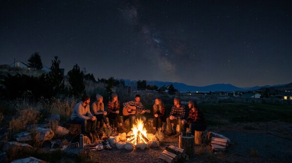 Un grupo de personas alrededor de una fogata por la noche bajo un cielo estrellado.