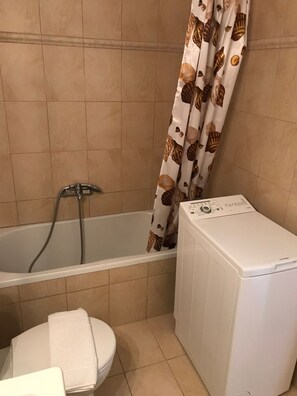 A bathroom with a bathtub, a toilet, and a washing machine. - Myrtos Cottages Melpomene (Divarata)