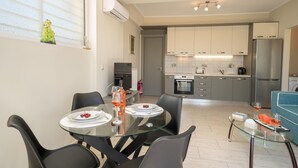 Una cocina moderna con electrodomésticos de acero inoxidable, un comedor con mesa de vidrio y un sofá azul.