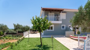 Una casa de dos pisos con un balcón, césped cuidado y jardín.