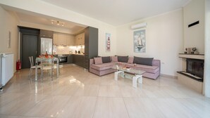 A modern living room with a glass coffee table, a pink sofa, and a fireplace. - Averto Apartment at Skala (Eleios-Pronnoi)