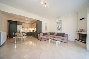 A modern living room with a glass coffee table, a pink sofa, and a fireplace. - Averto Apartment at Skala (Eleios-Pronnoi)