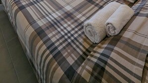 A bedroom with a bed, a wardrobe, a radiator, and a window with curtains. - Samaras Apartments Le Grand (Kamena Vourla)